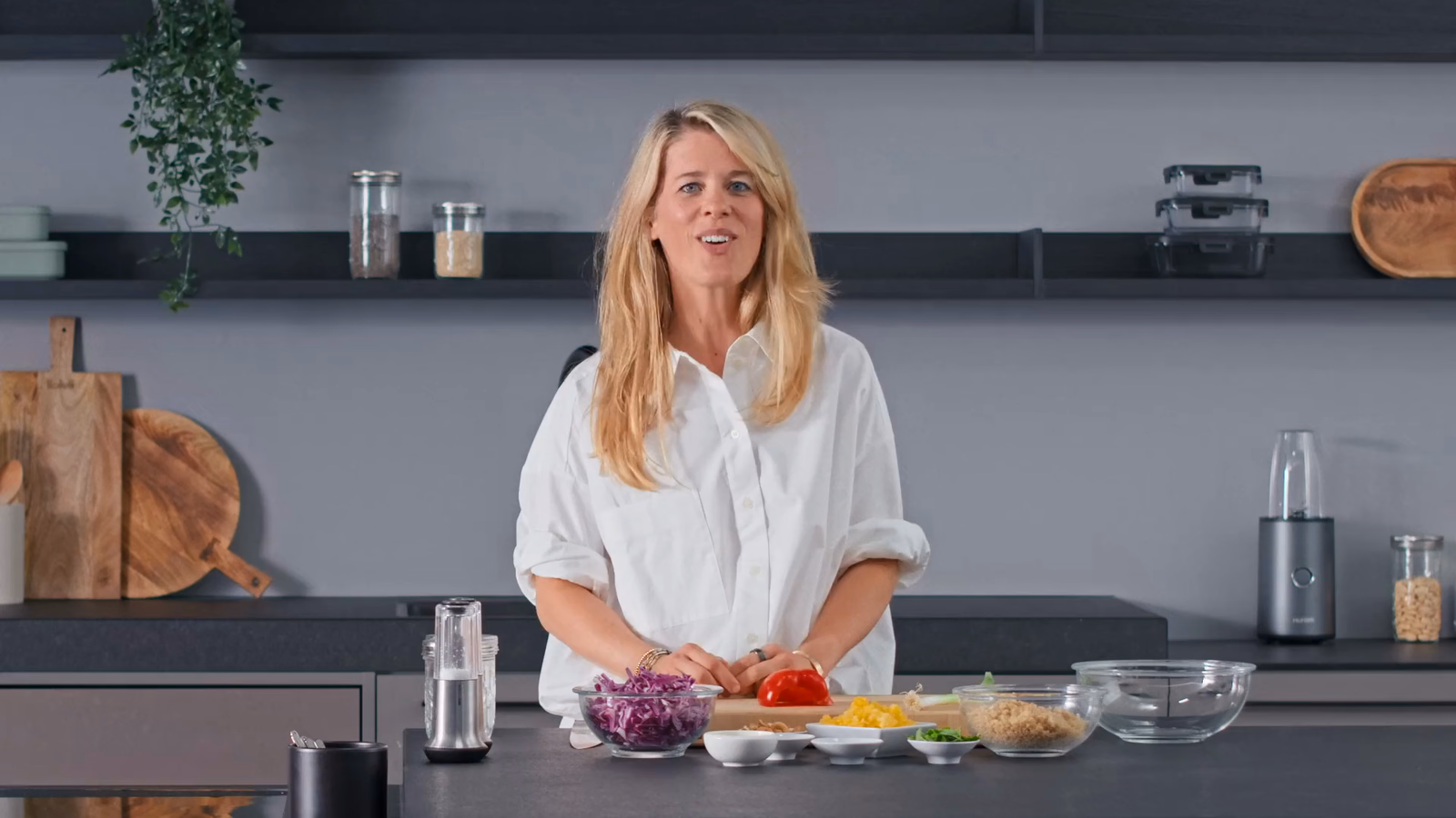 A 7hauben presenter in the studio kitchen, mid-sentence to camera with prepped ingredients in front of her — the kind of real footage Dubly dubs